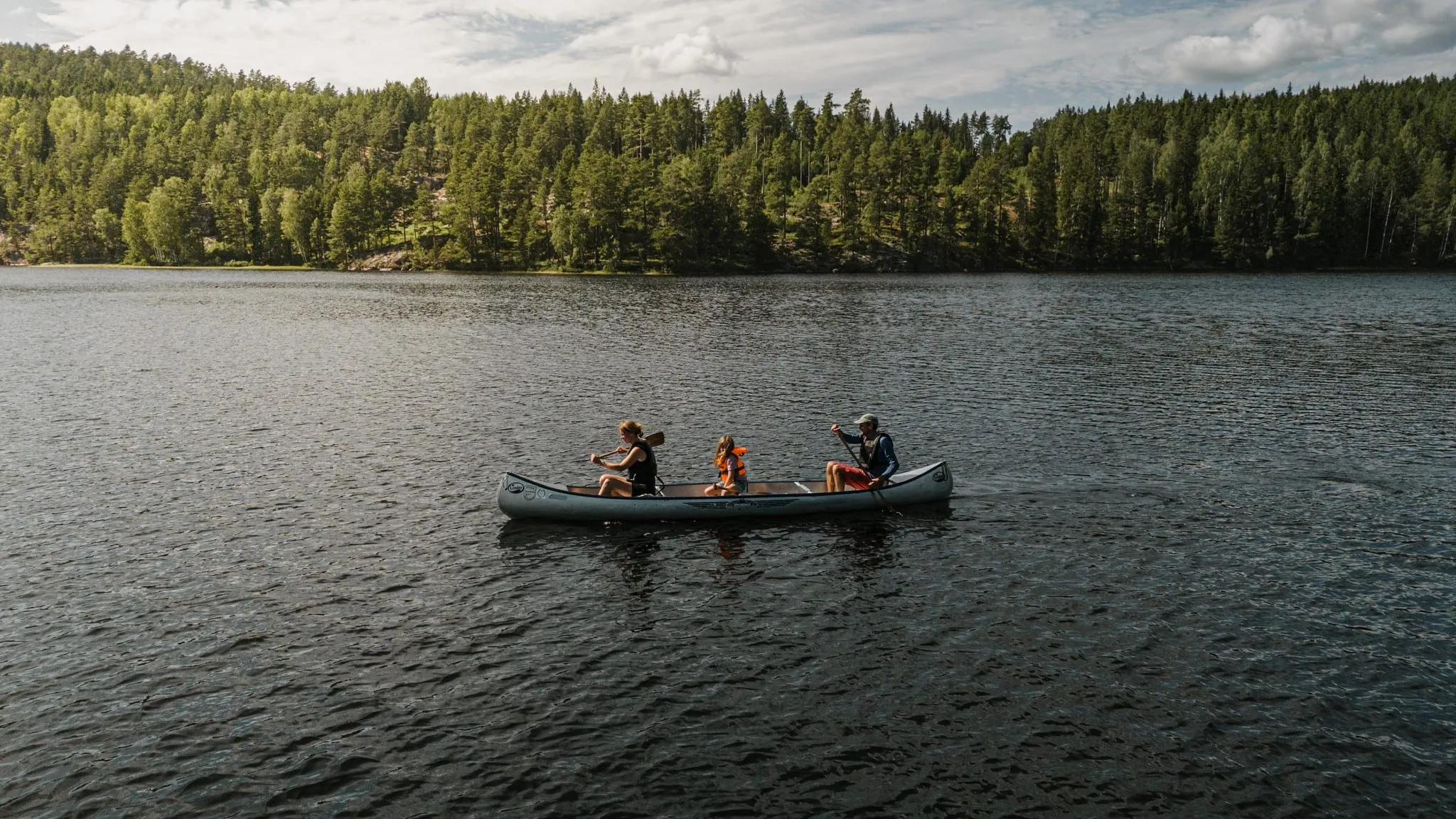 A family paddling a canoe on a forest lake