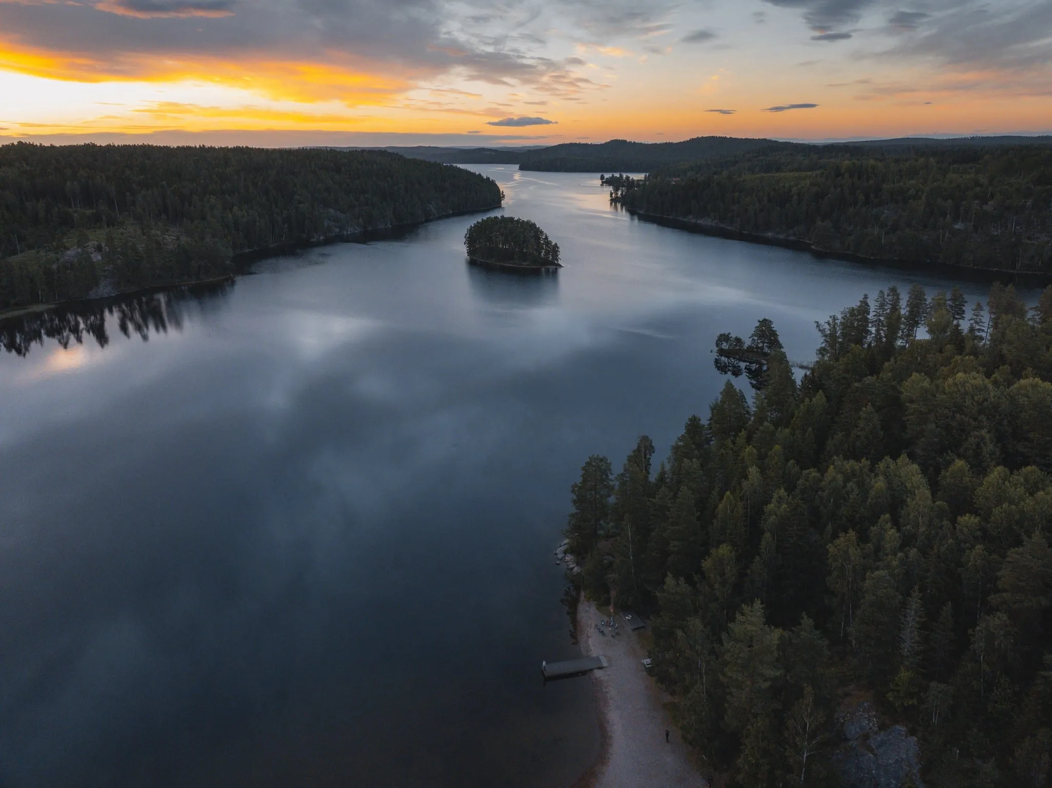Aerial view of a calm lake with forested islands at sunset